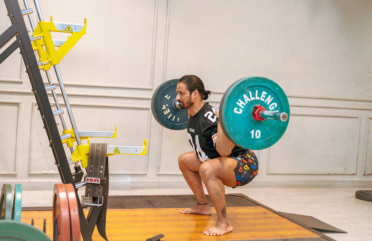 Modern sports facility with athletes training on indoor basketball court and weightlifting area