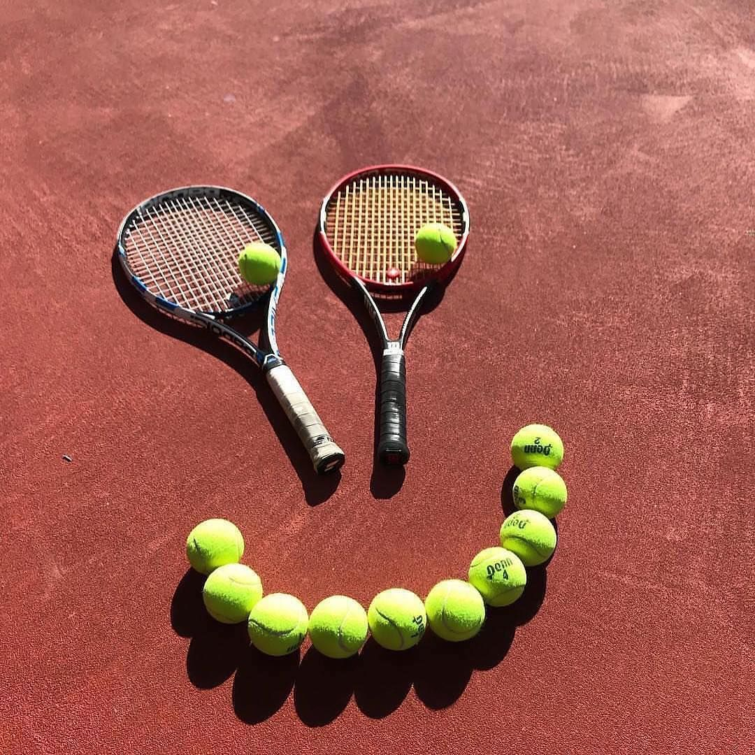 Tennis player serving the ball on a clay court during sunset